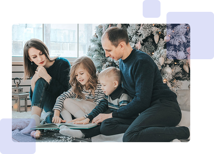 A family sitting on the ground with christmas decorations in background.