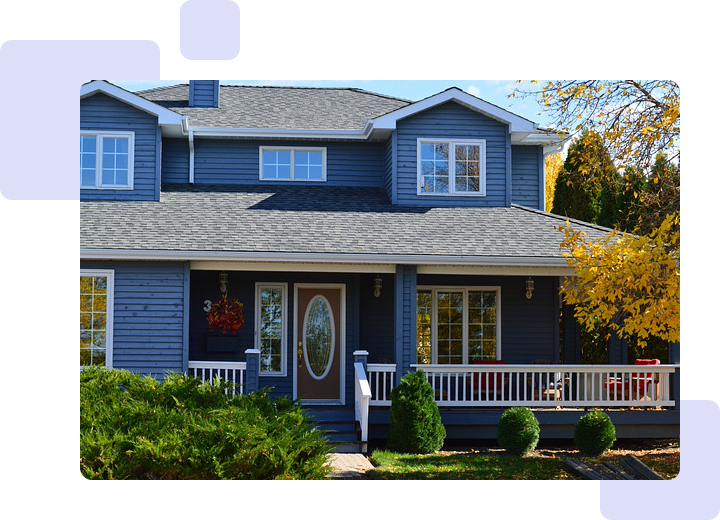 A blue house with green trim and bushes in front of it.